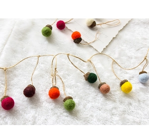 Macro detail of colorful wool felt acorns on hemp rope for Christmas tree decor