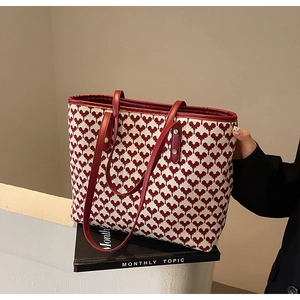 Detail of red heart pattern on beige woven tote bag with sturdy red shoulder handles