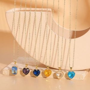 Macro shot of colorful heart and rectangular crystal pendants on gold necklaces