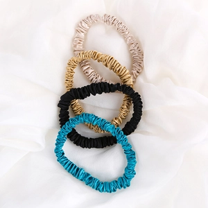 Set of four 22mm silk scrunchies in champagne, gold, black and peacock blue on white silk