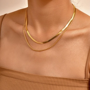 Close-up of double layer gold snake chain and rope necklace worn by a model