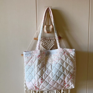 Detailansicht der gesteppten Tragetasche mit Blumenmuster, Anhänger und Textaufnäher