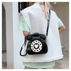 Detail of creative vintage telephone shaped crossbody bag in glossy black patent leather