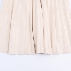 Vue détaillée de la texture plissée et de l'ourlet fluide d'une jupe midi beige