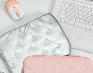 Close-up of quilted bow pattern on silver and pink laptop sleeves with zipper closure