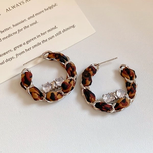 Détail des boucles d'oreilles C argentées tissées de tissu léopard avec pierres en zircon
