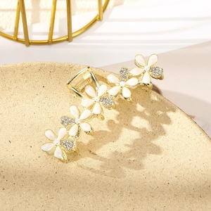Macro shot of gold-plated flower hair claw clip with white petals and pearls