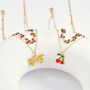 Double-layered gold necklace with sweet red cherry pendant and oil-pressed bow charm