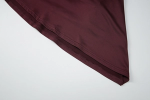 Détail montrant les coutures fines et l'ourlet d'une robe bordeaux dos nu ajustée