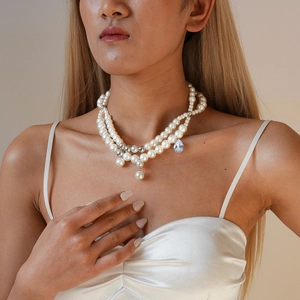 Close-up of double-layer pearl necklace with teardrop gemstone and silver beads