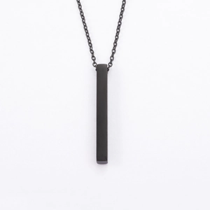 Detail of a minimalist black vertical bar pendant with polished finish on a link chain
