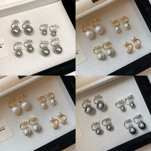 French luxury pearl ear clips in gold and silver finish displayed on a jewelry tray
