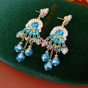 Dettaglio di orecchini vintage con cristalli blu e nappe di perle eleganti