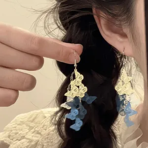 Gros plan détaillé de boucles d'oreilles papillon multicouches jaunes et bleues sur modèle