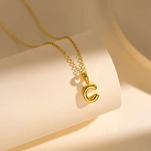 Elegant gold-tone chain necklace featuring a 3D bubble letter C pendant on white blocks