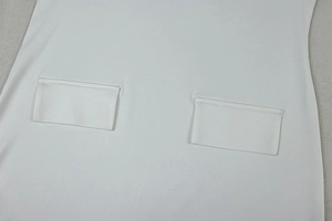 Detail of white halter dress featuring symmetrical rectangular pockets and neat stitching