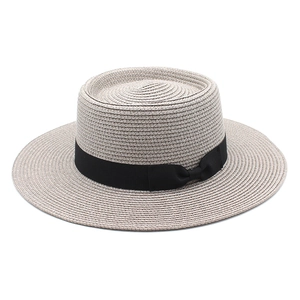 Detail of fine straw weaving and black ribbon bow on light beige boater hat