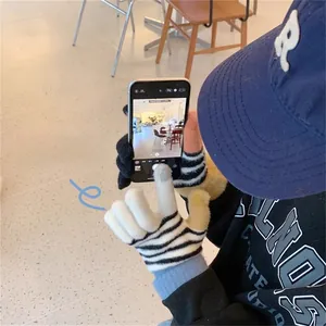 Close-up of black and white striped touchscreen knit gloves being used on a smartphone