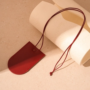 Macro shot of red leather key pouch with smooth texture and hanging lanyard strap