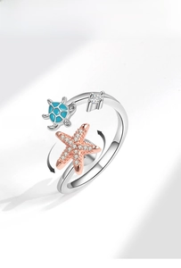 Detail view of rotating ring with turquoise enamel turtle and rose gold starfish charm