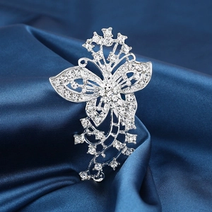 Detailed view of silver butterfly brooch with rhinestones on dark blue silk fabric