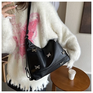 Dettaglio borsa tote in pelle nera con ciondoli a fiocco argento indossata da una modella