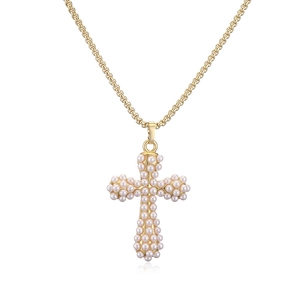 Gros plan du pendentif croix dorée avec petites perles sur un collier à chaîne maille