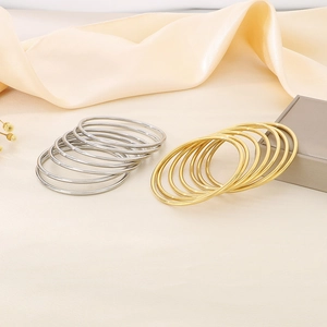 Detail shot of stackable 18K gold and silver plated round bangles on silk fabric
