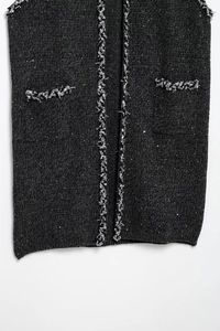 Détail de gilet en tweed gris foncé avec bordure tissée argentée, sequins et poches