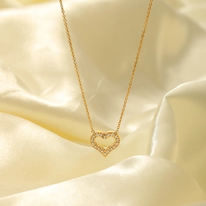 Gold hollow heart pendant necklace with zircons on elegant champagne silk background