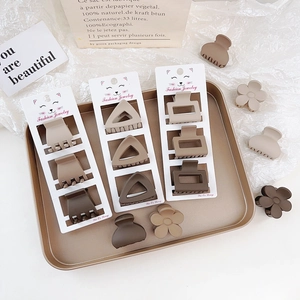Detailed set of matte earth-toned hair claws in various geometric shapes on a gold tray