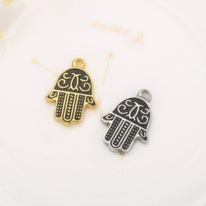 Macro shot of gold and silver Hamsa Hand pendants with black oil drip details for DIY