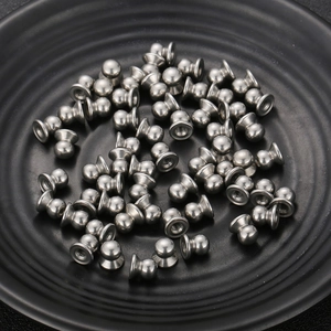 Bulk silver stainless steel bell-shaped hardware fittings and screw parts on a black tray