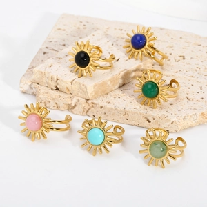 Close-up of vintage sunburst rings with colorful gemstones on a stone surface
