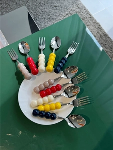 Flat lay of 304 stainless steel cutlery set with colorful beaded ceramic handles on a plate