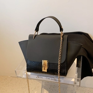 Detail of black wing bag showing crocodile embossed leather texture and gold chain strap