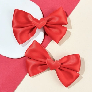 Paire de barrettes nœuds en satin rouge avec cœurs sur support minimaliste moderne