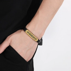 Detail of black leather bracelet with gold plate and Greek fret pattern engraving
