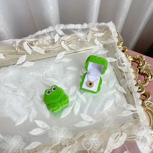 Macro detail of cute green frog velvet jewelry box on vintage mirror tray with lace décor