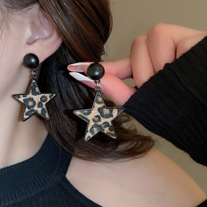 Gros plan de boucles d'oreilles étoile léopard portées par un mannequin élégant