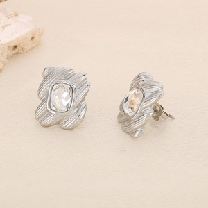 Macro view of geometric silver titanium earrings with radiant crystal and wavy texture