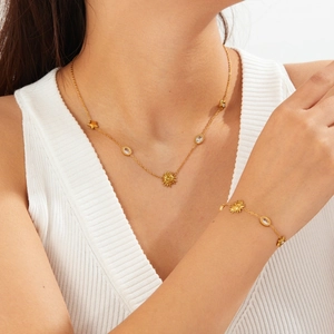Detail shot of the gold sun pendant and crystal necklace worn by a model on white background