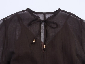 Detail of dark brown chiffon neckline with tie-up strings and gold metal beads