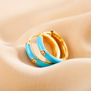 Macro detail of sky blue enamel gold hoop earring with a central clear zircon inlay