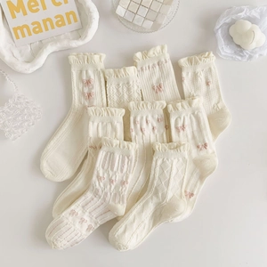 Detail of white ruffle socks featuring knit textures and cute pink bow accents