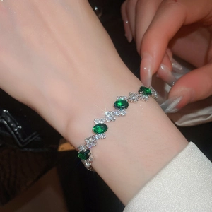 Macro shot of silver bracelet featuring oval emerald green stones and white zircons