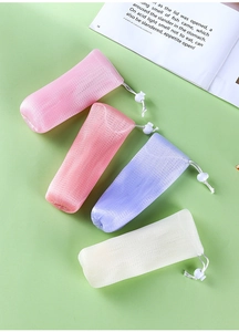Detail of four colorful mesh soap foaming bags with drawstring closures on green background
