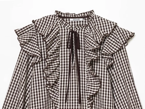 Detail of ruffled shoulders and neckline on a brown plaid shirt with dark brown tie cord