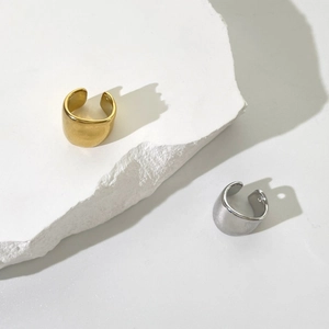 Minimalist horseshoe U-shaped 18K gold and silver ear cuffs on white stone base