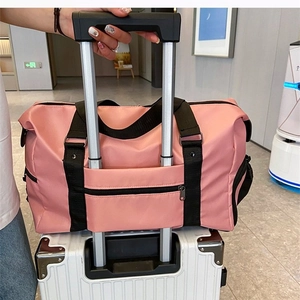 Pink large gym bag with trolley sleeve attached to a suitcase for travel convenience